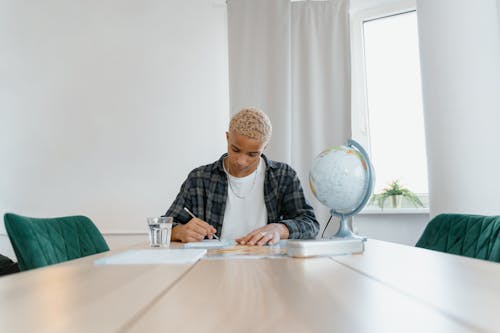 A Young Man Studying on a Table Indoors