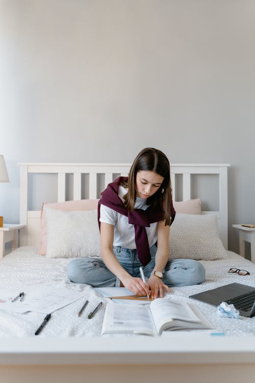 Free A Young Woman Studying in Bed Stock Photo