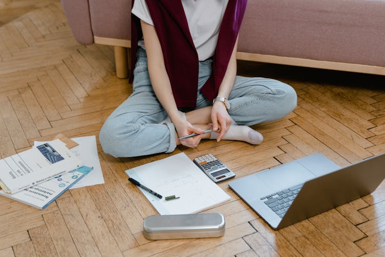 A Student Taking An Online Class While Sitting On The Floor