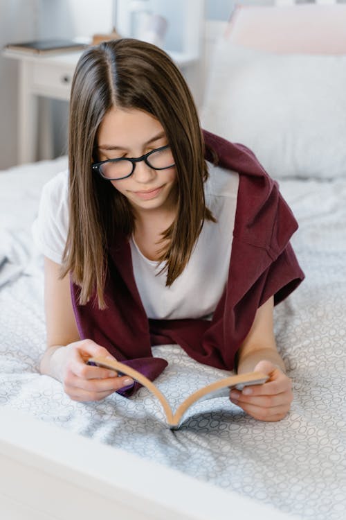 A Young Woman Reading a Book on a Bed