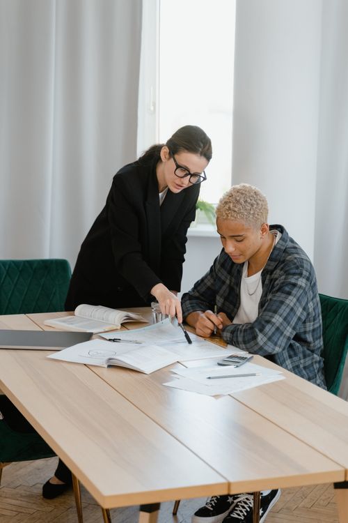 Free A focused learning moment between a teacher and student discussing at a desk. Stock Photo