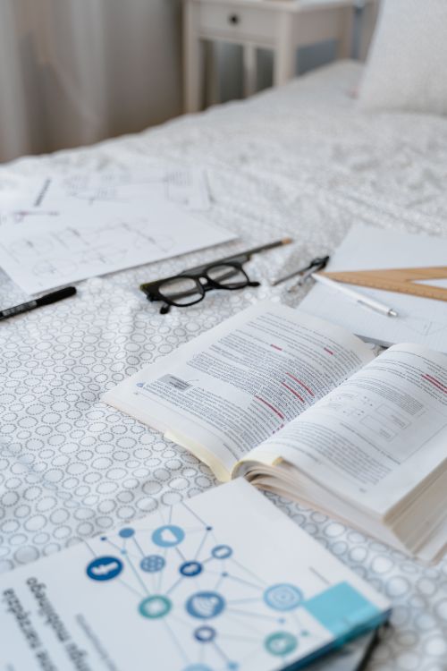 Free Books, glasses, and study materials arranged on a bed, ideal for learning themes. Stock Photo