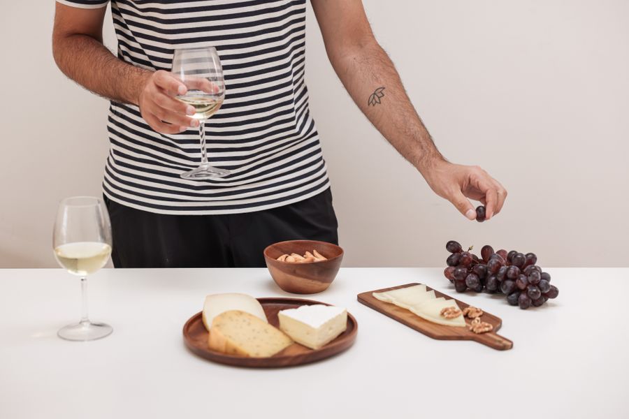 Calice di vino con formaggi, uva e frutta secca su tavolo