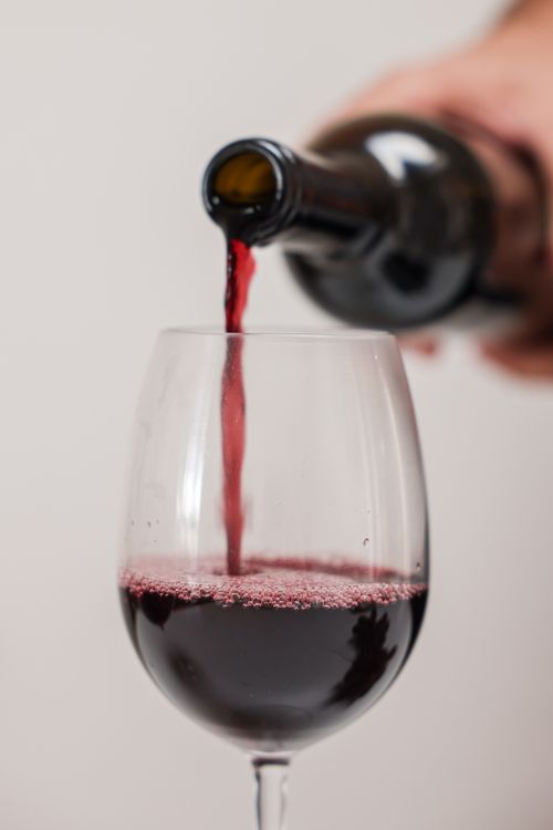 Free Close-up shot of red wine being poured into a glass. Perfect for wine-related themes. Stock Photo