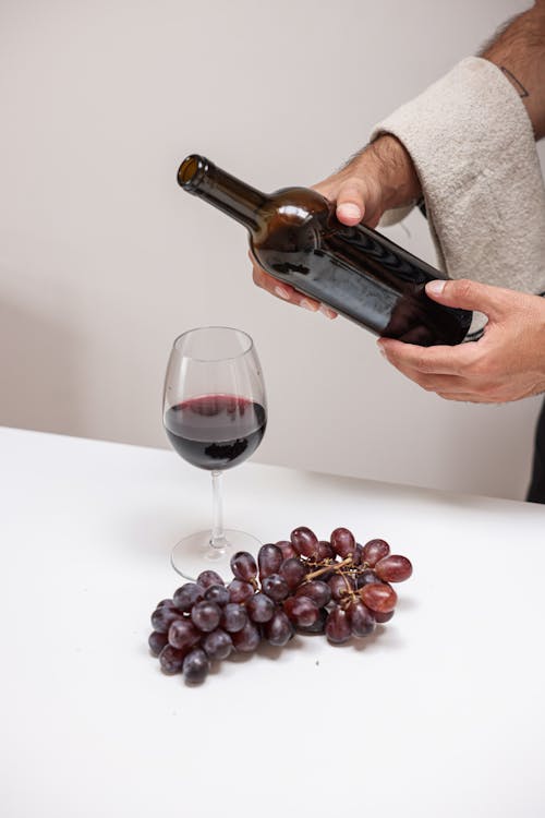 A Person Holding Wine Bottle Near the Wine Glass