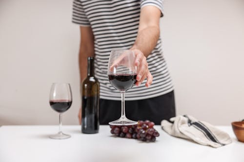 A Person in Striped Shirt Holding a Glass of Wine