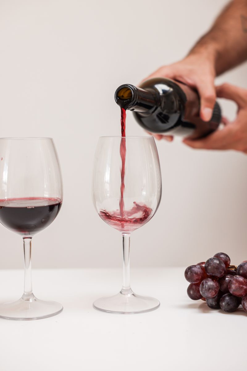 Guest holding two glasses of red wine at a tasting