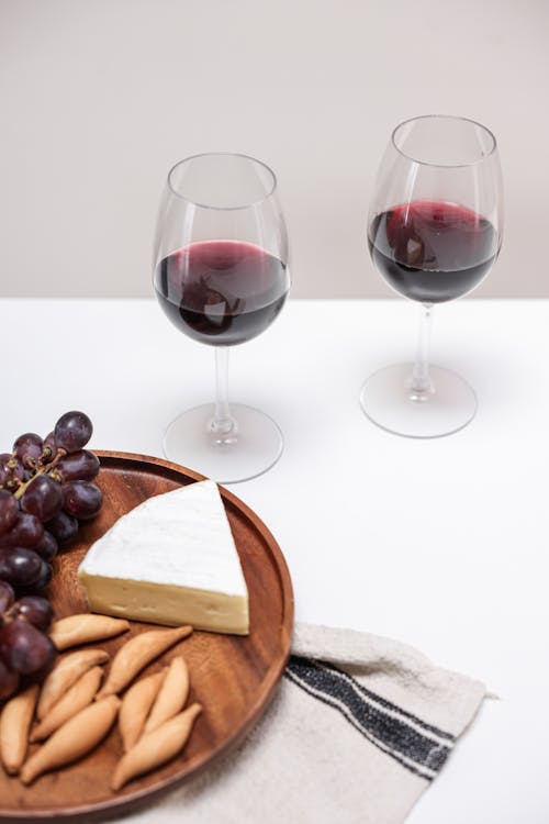 Free A Wine Glasses Near the Wooden Plate with Cheese and Grapes Stock Photo