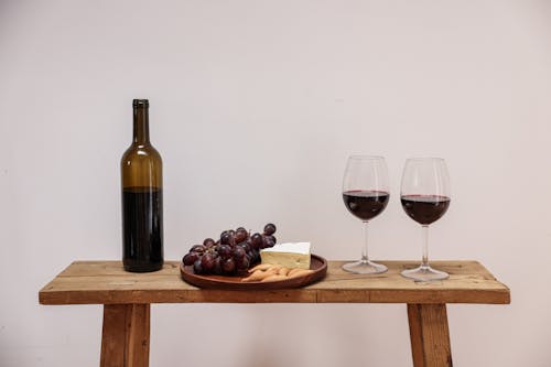 Free A Wine Bottle Near the Wooden Plate with Cheese and Grapes Stock Photo