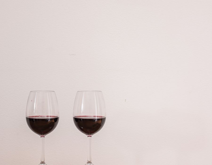 Two glasses of wine against a plain warm background