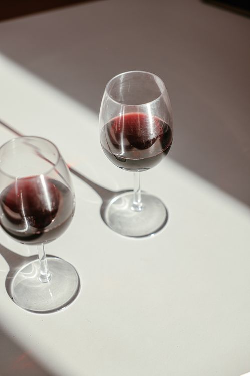 Free Two red wine glasses casting shadows on a minimalist table. Perfect for wine-related content. Stock Photo