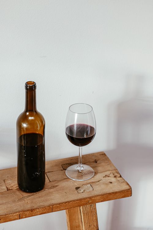 Free A bottle of red wine with a filled glass on a rustic wooden table, showcasing elegant simplicity. Stock Photo