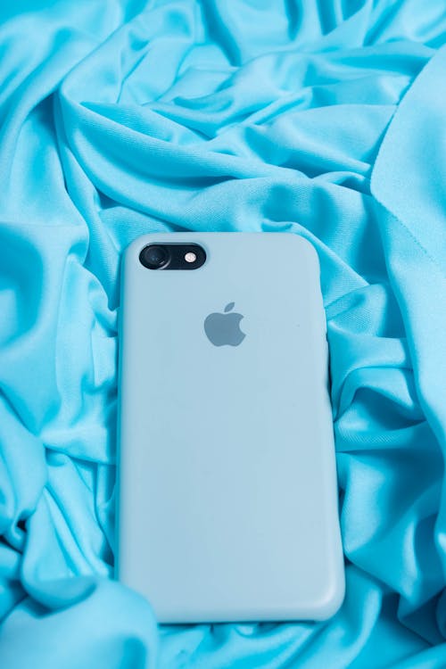 From above of modern cellphone in light blue case on creased silk fabric