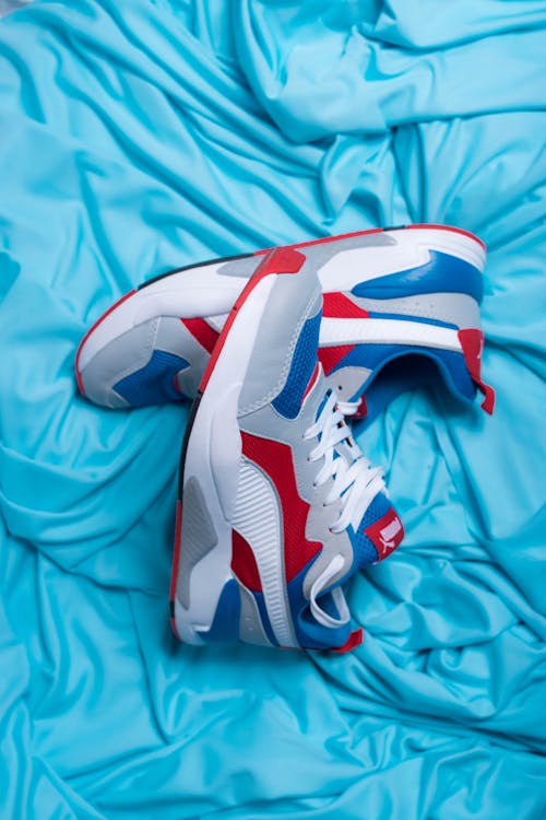 Free Top view of pair of modern sneakers with bright red and blue parts on creased cloth Stock Photo