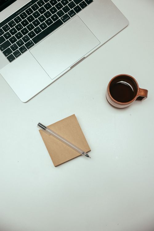 Free Top view of a minimalist desk setup with a laptop, coffee, and notepad. Stock Photo