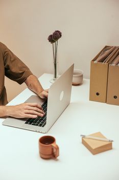 A cozy home office setup with a person typing on a laptop at a tidy desk.