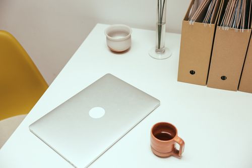 Free A minimalist home office desk setup with laptop, coffee cup, and file organizers. Stock Photo