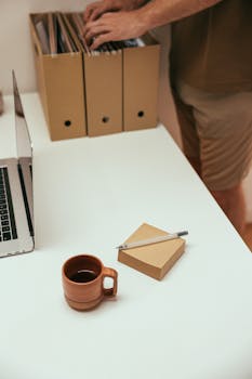 A desk setup featuring coffee, files, a laptop, and office supplies for productive work.