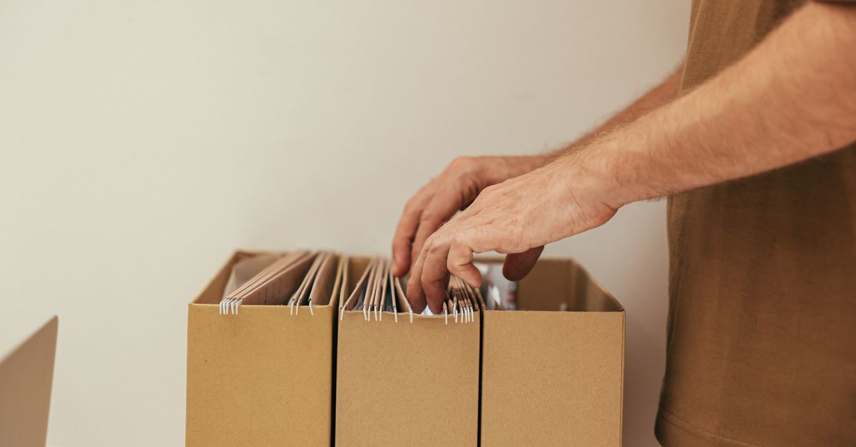 Close-up of a person organizing files in cardboard boxes, ideal for business and office themes.