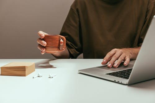 Free A Person Having a Cup of Coffee while Using a Laptop Stock Photo