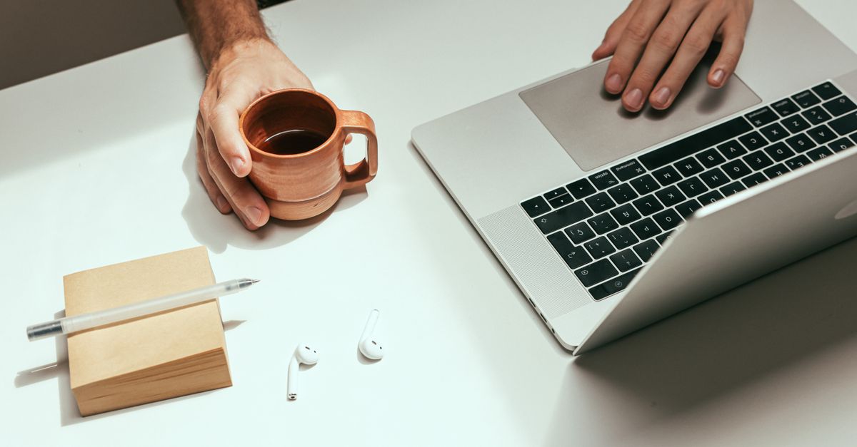 person working slowly at wooden desk with coffee and notebook, soft morning light