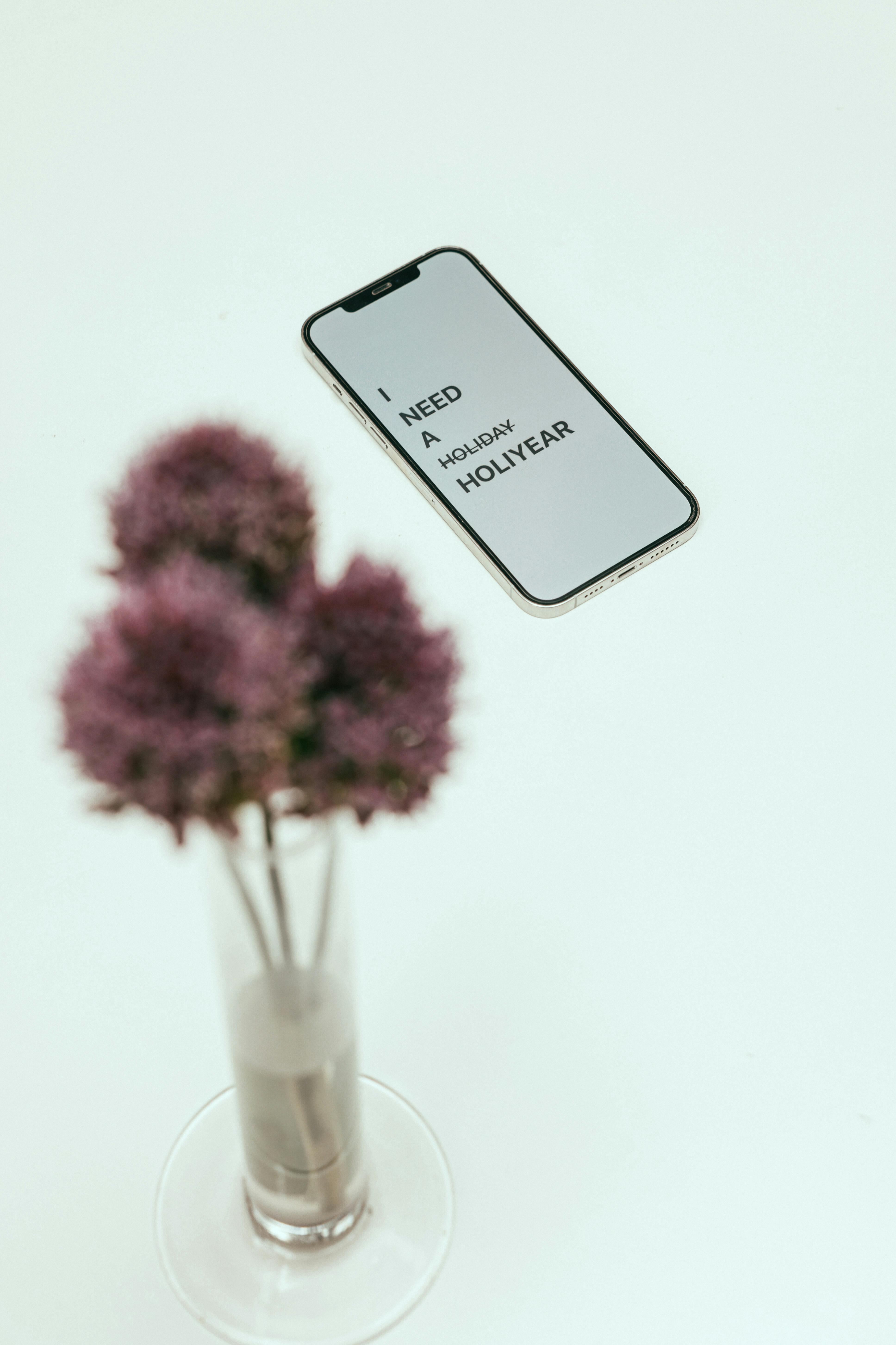 a smartphone beside flowers in a vase