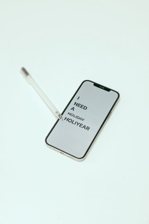 Free A smartphone displaying a humorous holiday message with a pen on a white background. Stock Photo