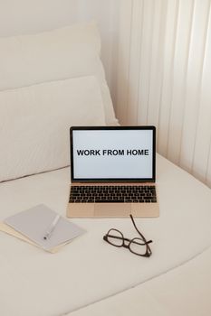 A simple work from home setup featuring a laptop on a bed. Ideal for remote work themes.