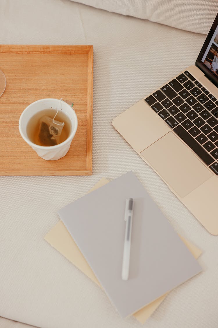 A Laptop Beside Notebooks And Cup Of Tea