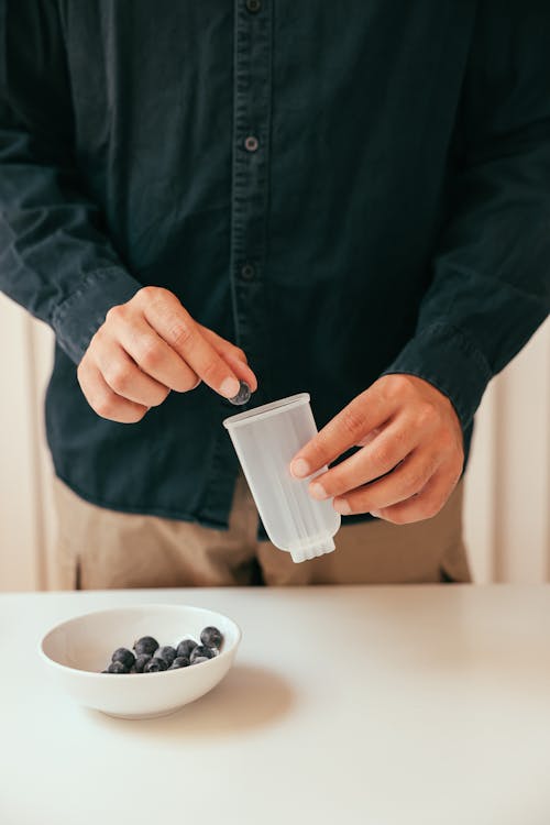 A Person Putting Huckleberries on a Popsicle Mold