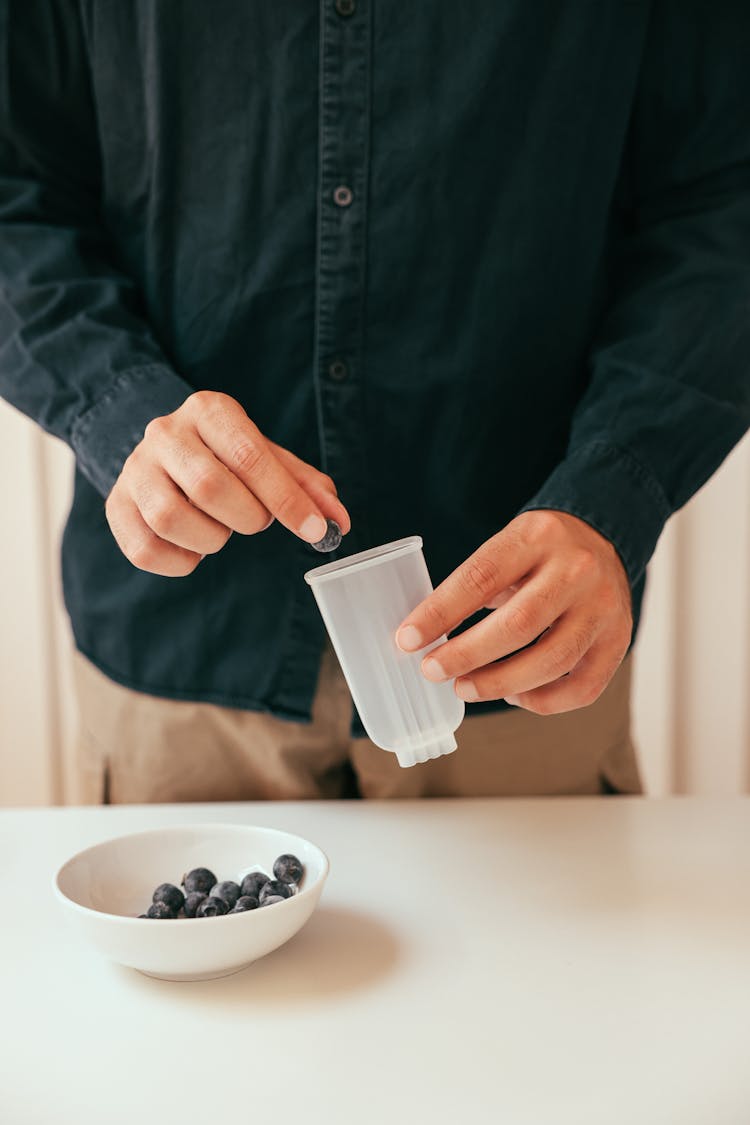 A Person Putting Huckleberries On A Popsicle Mold