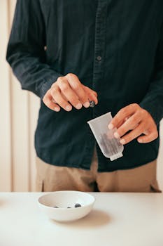 A person transfers fresh blueberries from a container to a bowl.