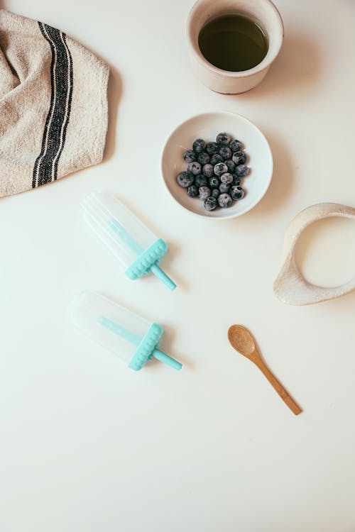 Wooden Spoon by Bowl with Blueberries on White Table