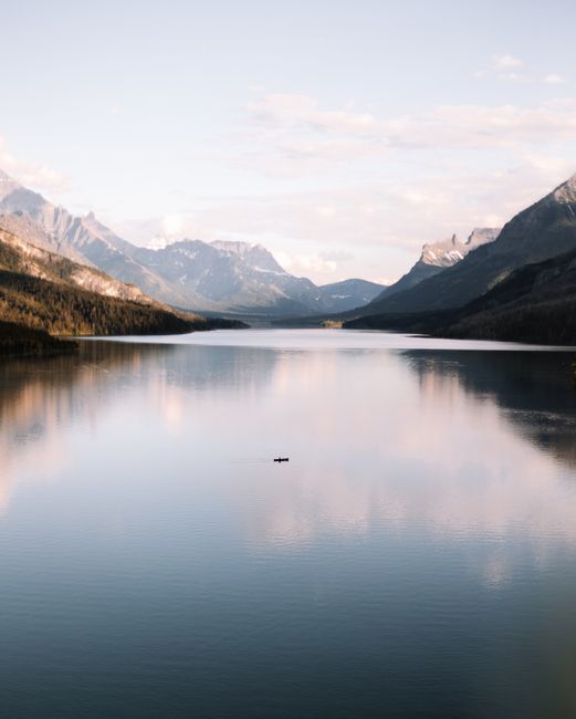 Peaceful mountain lake scene at Waterton Park, Alberta, showcasing serene reflections and distant mountains.