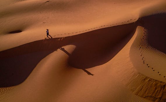 日落时分，一个人孤身走过沙丘，在沙漠中投下长长的影子