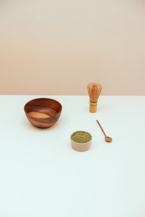 Bowl, Whisk and Spoon by Matcha Powder on Table