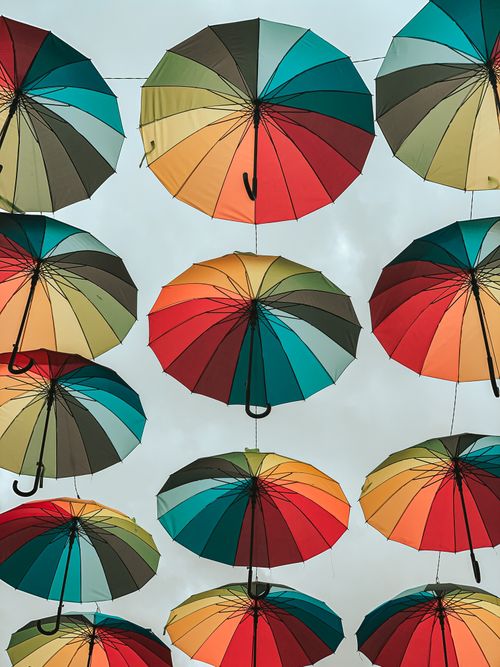 Free Artistic arrangement of colorful umbrellas hanging outdoors, creating a vibrant and striking visual pattern. Stock Photo