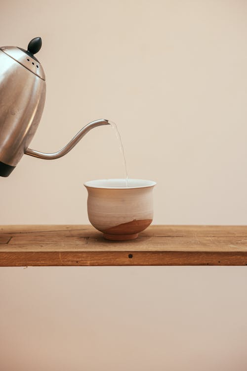 Water  From Teapot Being Poured into a White Ceramic Cup 