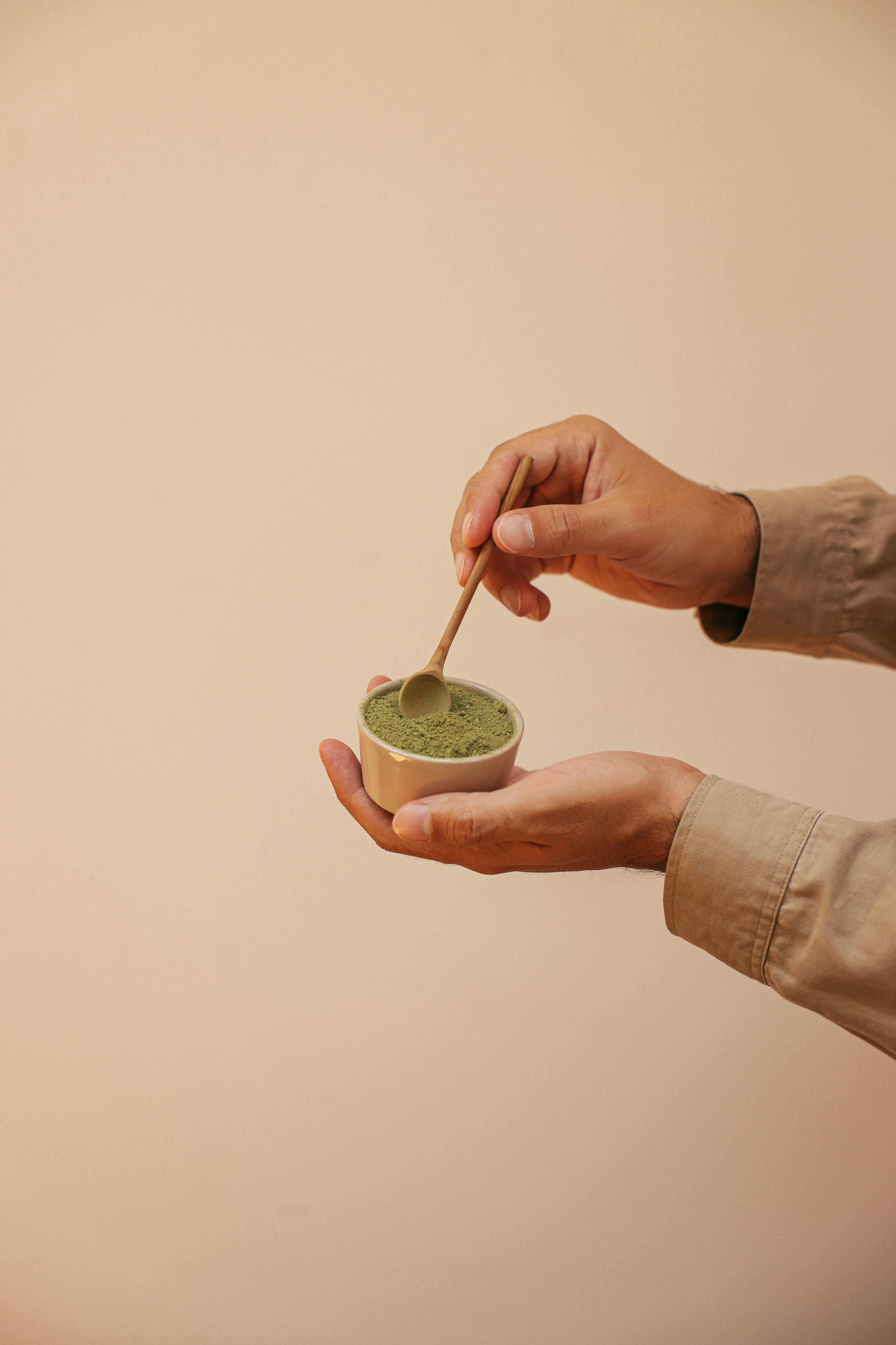 person holding a cup with matcha powder