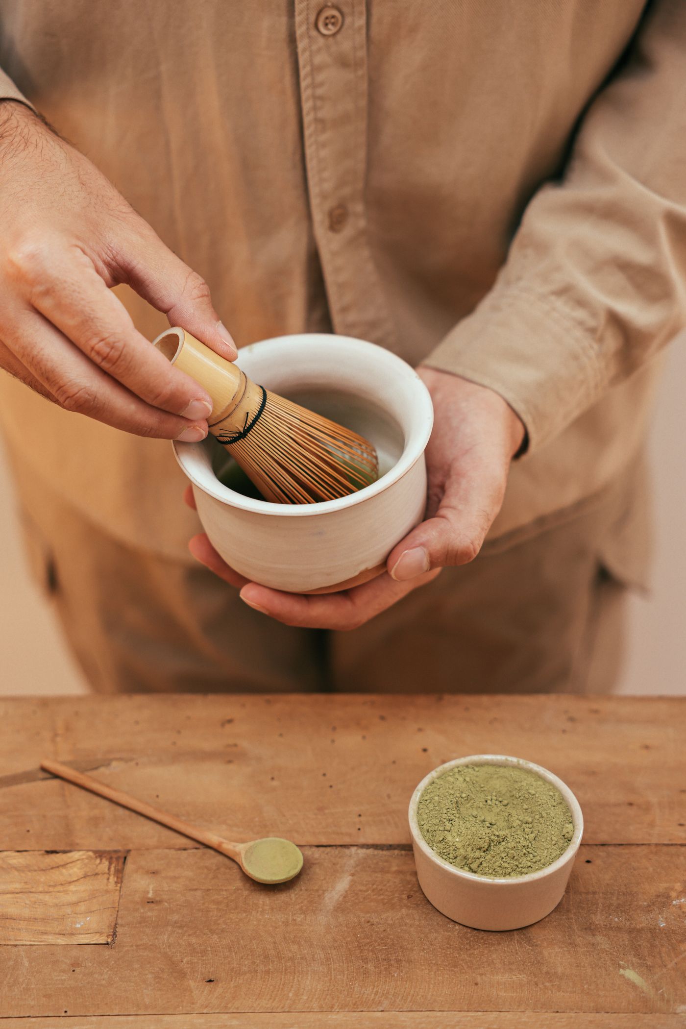 Hands whisking matcha with a bamboo chasen