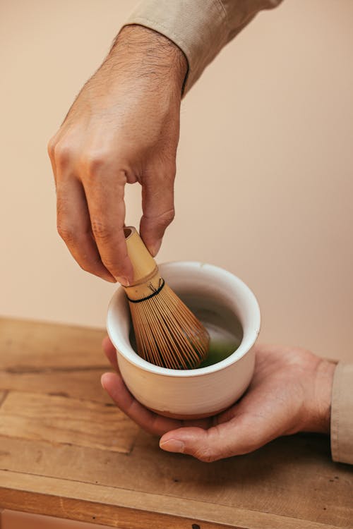 Person Mixing Green Tea on Ceramic Bowl