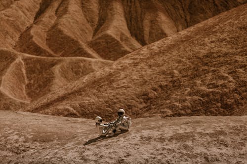 Astronauts in Mars Holding Hands while Sitting on the Ground