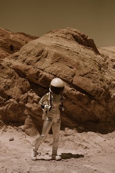 Astronaut in spacesuit exploring a barren, rocky landscape reminiscent of Mars.