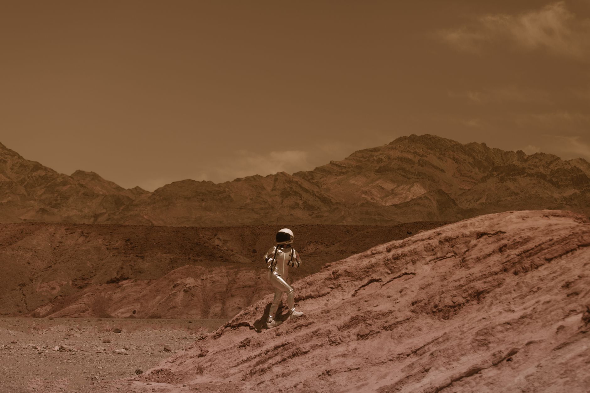 Astronaut walking on a barren landscape resembling Mars, with futuristic and adventurous vibes.