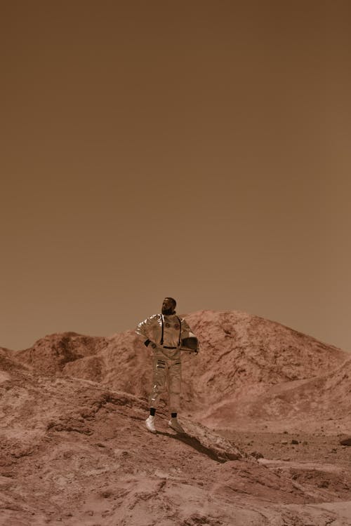 Free A Man Standing on a Rock Formation Wearing a Space Suit Stock Photo