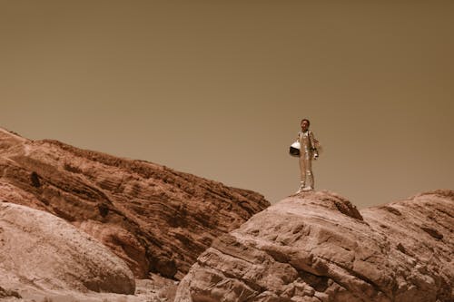 A Woman Holding Her Helmet while Standing on the Rock