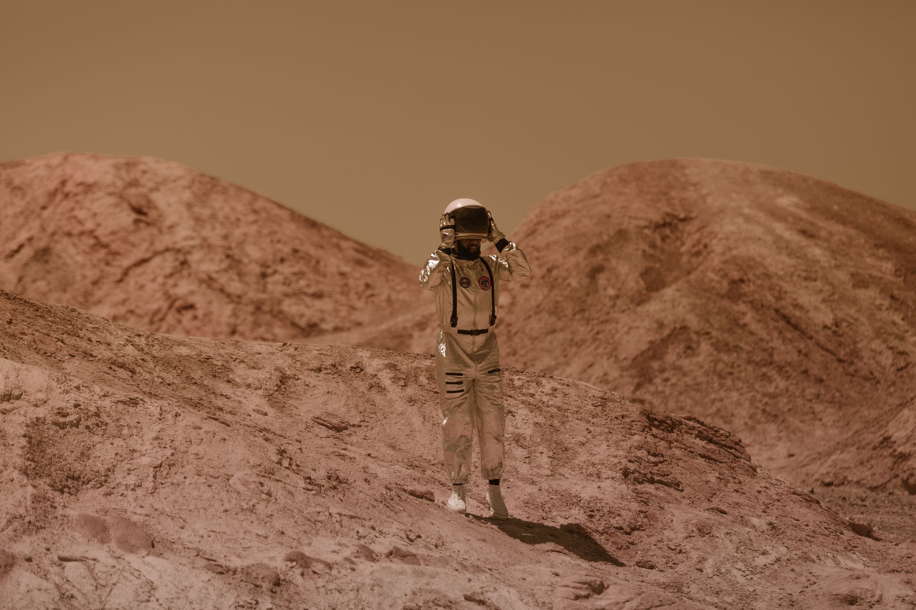 Astronaut in detailed spacesuit explores a Mars-like rocky landscape outdoors, evoking sci-fi adventure.
