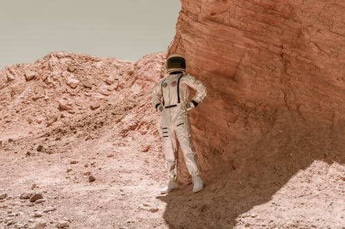 A Person Wearing a Space Suit Standing in front of a Rock Formation