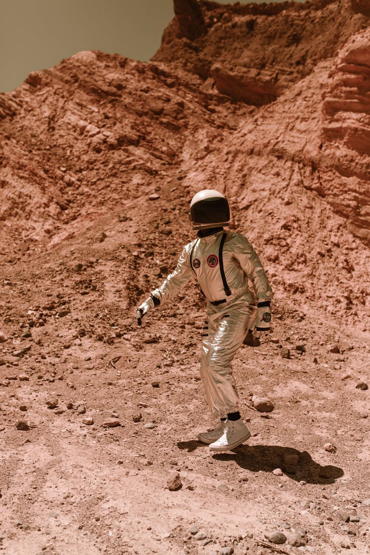 An Astronaut Walking On Dry Rocky Land