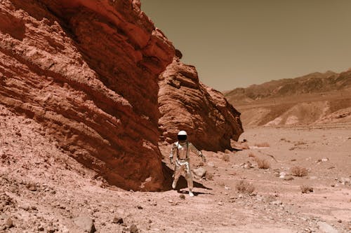 Astronaut in a Spacesuit Standing next to a Rock Formation on Mars 